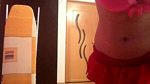 In the bedroom, she teases with her shaved pussy under the miniskirt.