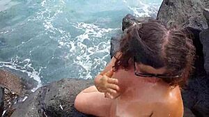 Unexpected cumshot hits a nudist's face on the beach from her lover