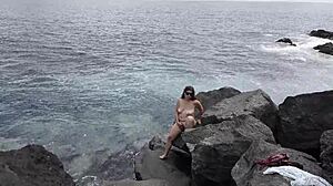 Unexpected cumshot hits a nudist's face on the beach from her lover